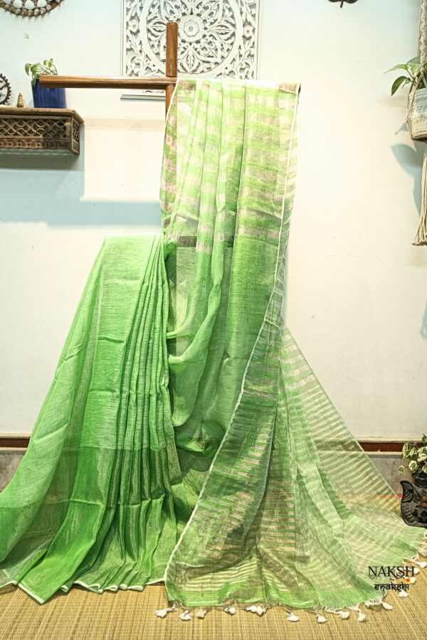 Step into elegance with our sophisticated tissue linen sarees, adorned in classy pastel shades that exude timeless charm. Crafted with airy, breathable linen, these sarees ensure comfort while making a striking statement with their unique silver zari stripes. Perfect for any occasion, from casual gatherings to formal events, these sarees are versatile and effortlessly stylish. Each saree comes with a matching blouse piece, completing the ensemble with grace and finesse. Elevate your wardrobe with these exquisite pieces that blend luxury with comfort seamlessly. this is a green linen saree.