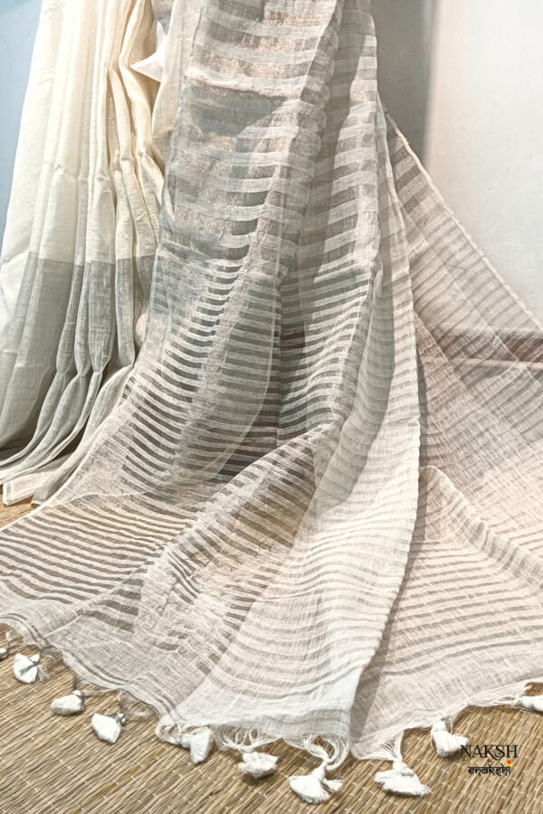 zari stripes white or off white linen saree organic linen saree with blouse piece. Step into elegance with our sophisticated tissue linen sarees, adorned in refreshing pastel shade of mint green that exude timeless charm. Crafted with airy, breathable linen, this saree ensure comfort while making a striking statement with their unique silver zari stripes. Perfect for any occasion, from casual gatherings to formal events, these sarees are versatile and effortlessly stylish. this saree comes with a running blouse piece, completing the ensemble with grace and finesse. Elevate your wardrobe with these exquisite pieces that blend luxury with comfort seamlessly.