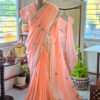 Full length peach blossom pure cotton handloom saree with all over teal embroidery motifs gold scallop border and white tassels displayed on mannequin by Naksh by Enakshi