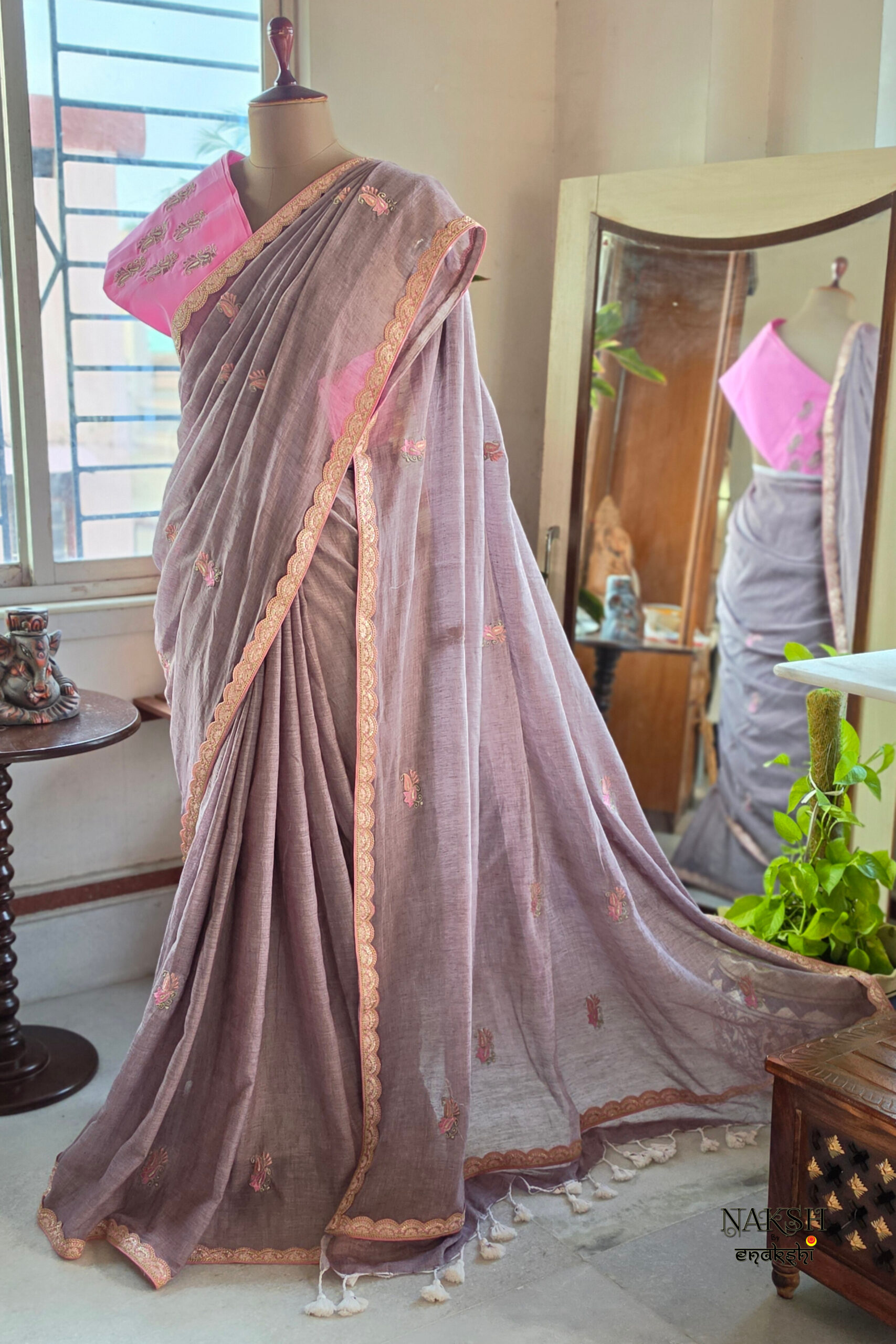 Smoky mauve pure cotton handloom saree with multicolor embroidery motifs gold pink scallop border and contrast bubblegum pink embroidered blouse piece displayed on mannequin by Naksh by Enakshi